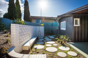 Ein Wohngarten mit einer Ziegelmauer, einem blauen Zaun und einem Garten mit trittfesten Steinen.