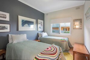Ein Schlafzimmer mit zwei Betten, einem Fenster mit Aussicht und gerahmten Bildern an der Wand.