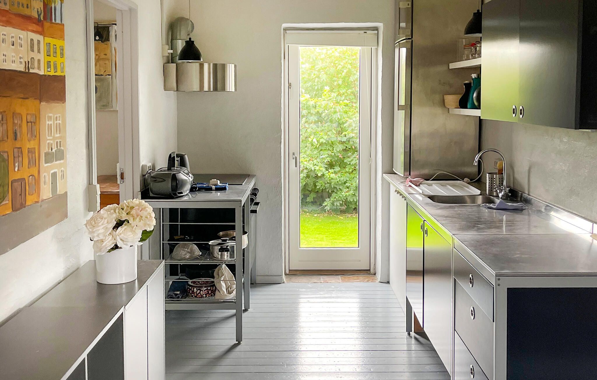 A modern kitchen with a built-in oven, a sink, and a window with a view of greenery.