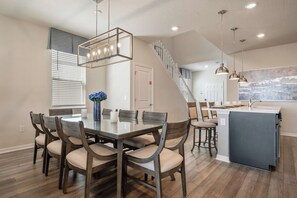 Une cuisine moderne dotée d’un îlot central, de luminaires suspendus et d’un escalier menant à un niveau supérieur.