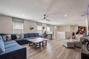 A spacious living room with a blue sofa, a wooden coffee table, and a ceiling fan. - NEW Disney Clubhouse & Themed BR I Near Clubhouse (Davenport)