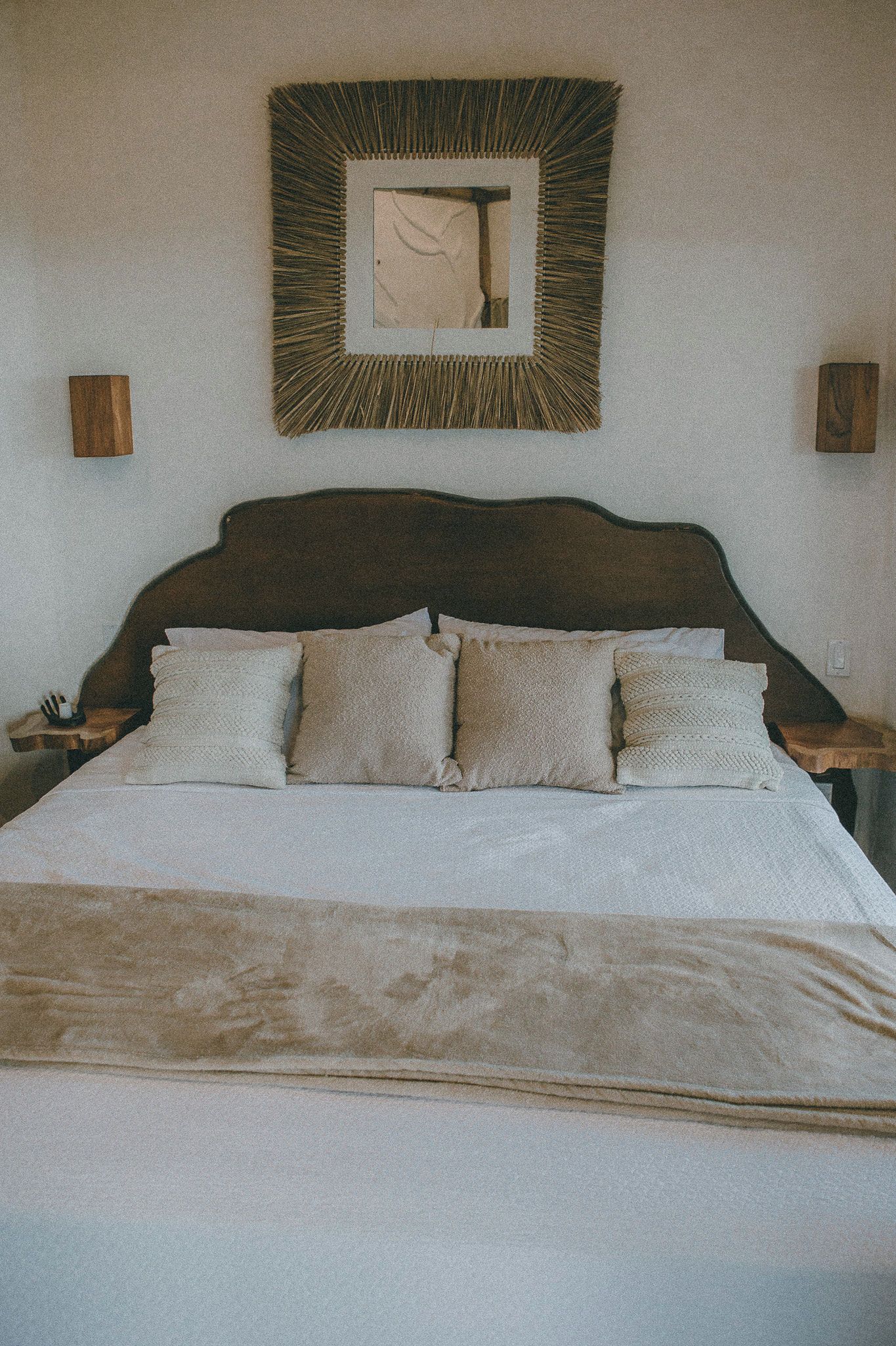 Un letto con testiera, diversi cuscini e una coperta.