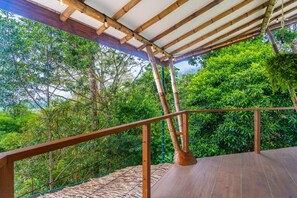 Um deck de madeira com guarda-corpo, rodeado por vegetação exuberante.