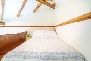 A bedroom with a wooden headboard, a bed with a white and blue striped bedspread, and a small plant on the nightstand. - Earth Home with Waterfall Jungle View above Uvita Beach with River, Sauna, Yoga (San Luis)
