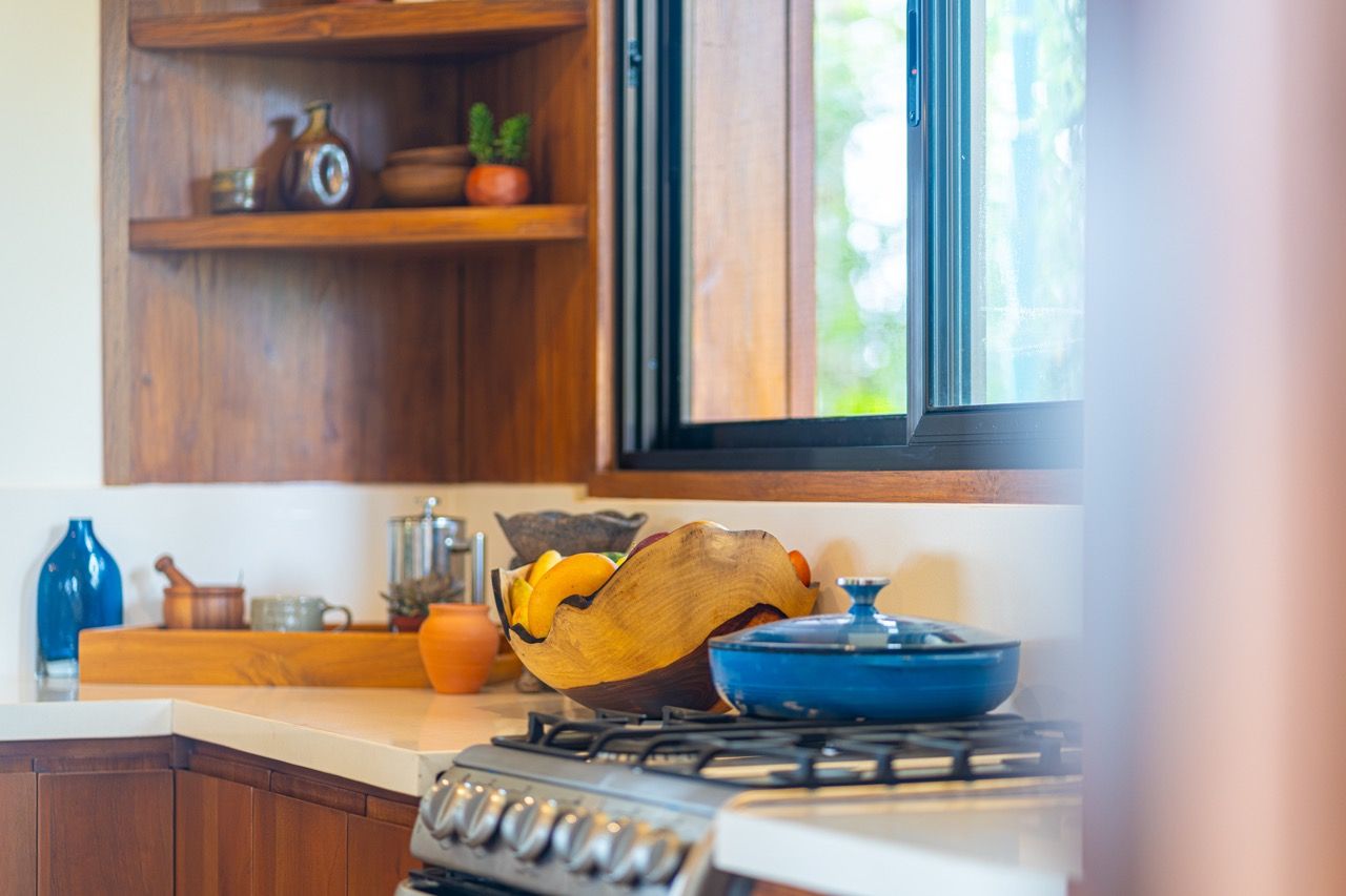A kitchen with wooden cabinets, a gas stove, a blue pot, and a wooden bowl on the countertop.