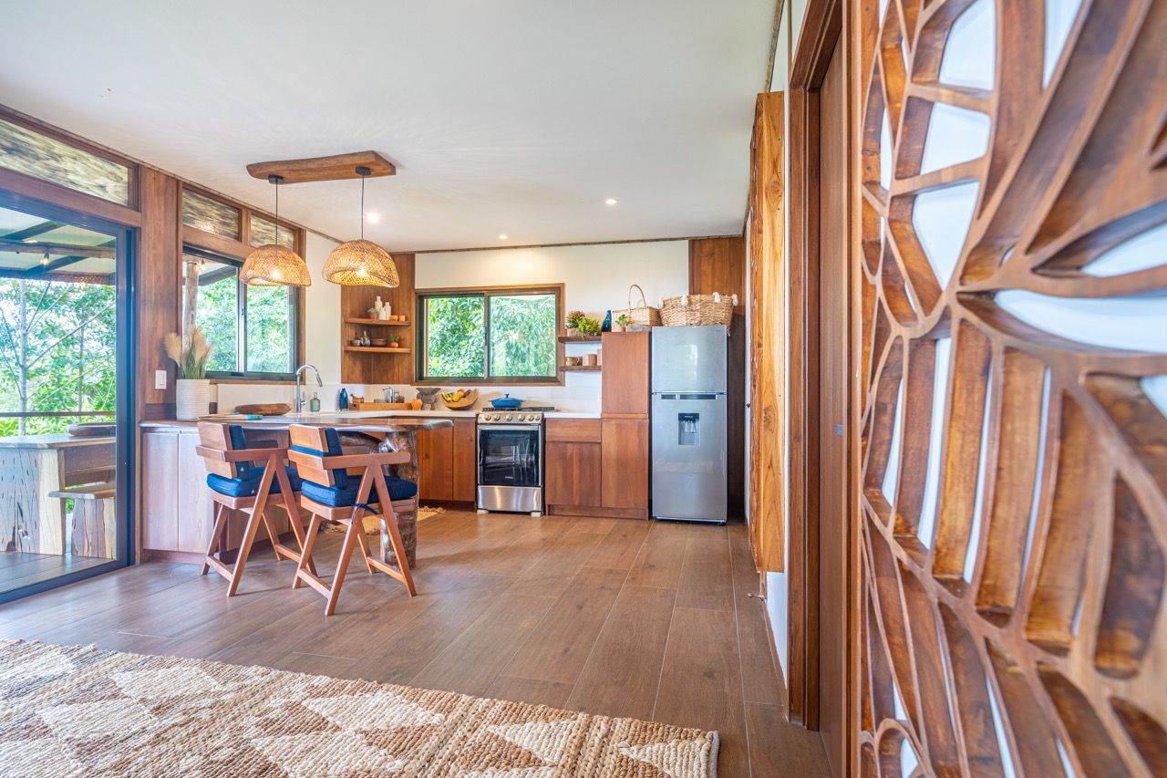 Una cucina moderna con mobili in legno, un frigorifero in acciaio inossidabile e un'area pranzo con tavolo e sedie in legno.