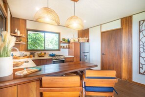 Cozinha com armários de madeira, uma ilha grande e luminárias de vime suspensas.