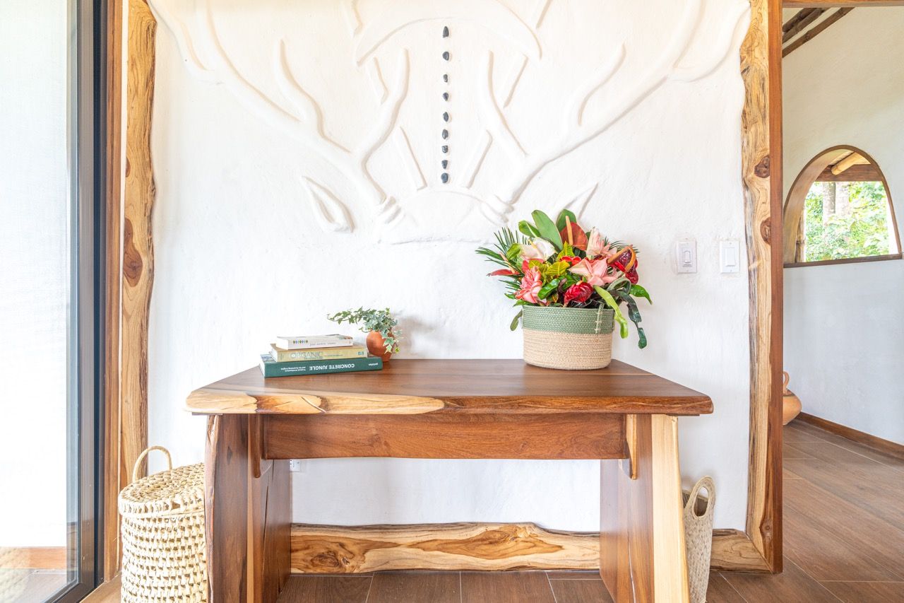 Una mesa de madera con una cesta tejida y una planta en maceta.