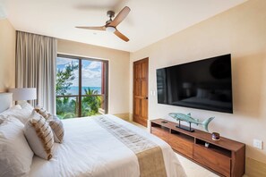 Une chambre d’hôtel avec un grand lit, un ventilateur de plafond, une télévision et une vue sur l’océan.