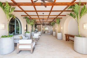 A corridor with seating, large planters, and a ceiling fan. - Artila Isla Mujeres: Your Sanctuary of Coastal Sophistication (Isla Mujeres)