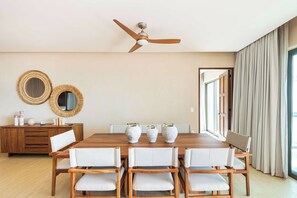 A dining area with a wooden table, white upholstered chairs, and a ceiling fan. - Artila Isla Mujeres: Your Sanctuary of Coastal Sophistication (Isla Mujeres)