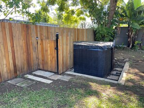 A wooden fence with a gate, a hot tub, and a garden area with grass and plants. - perfect position, well maintained home with added comforts for a luxurious stay (Sandgate)