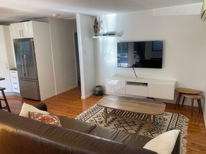 A modern living room with a brown leather sofa, a wooden coffee table, and a patterned rug. - perfect position, well maintained home with added comforts for a luxurious stay (Sandgate)