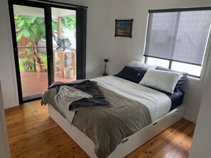 A bedroom with a bed, a window, a painting, and a view of a garden through a sliding door. - perfect position, well maintained home with added comforts for a luxurious stay (Sandgate)