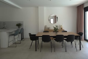 A modern dining area with a long table, black chairs, a kitchen area with a sink, and a large mirror on the wall. - Luxury Villa Mandy with Heated Pool, Jacuzzi & Sauna (Žrnovnica)