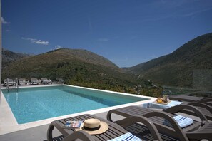 A pool area with lounge chairs and a view of a mountainous landscape. - Luxury Villa Mandy with Heated Pool, Jacuzzi & Sauna (Žrnovnica)