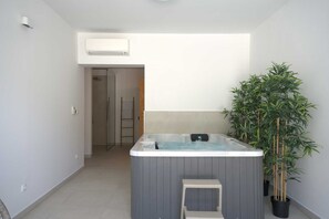 Een compacte badkamer met een douche, bad en een potplant.