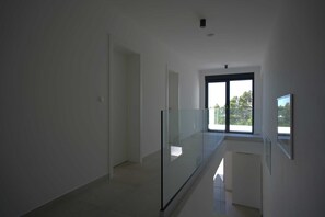 Een modern interieur met een glazen balustrade, een deur en een groot raam.