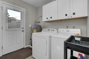 A laundry room with a white door, two stacked washing machines, and a cabinet above.