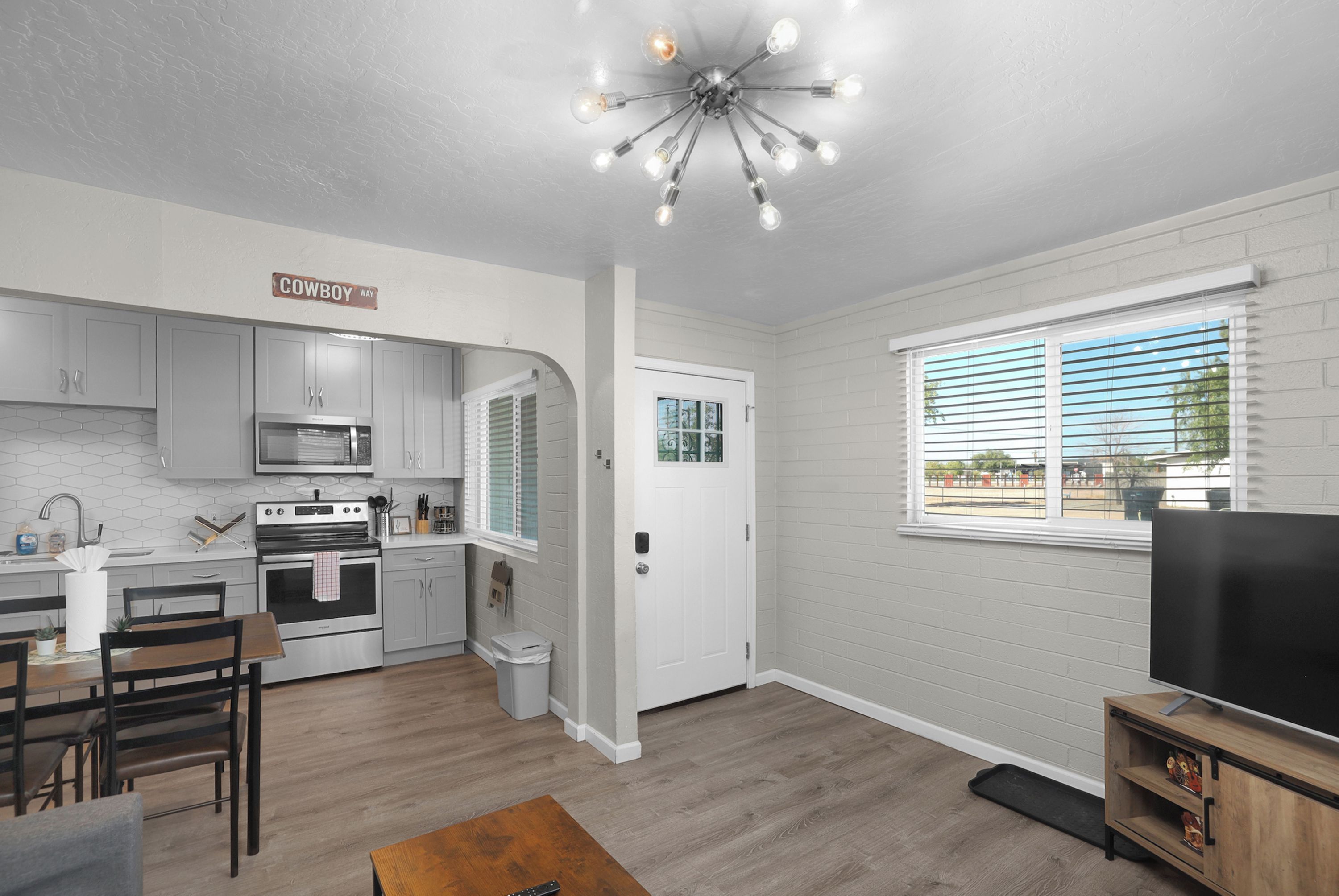 A modern kitchen with a microwave, oven, and dining area.