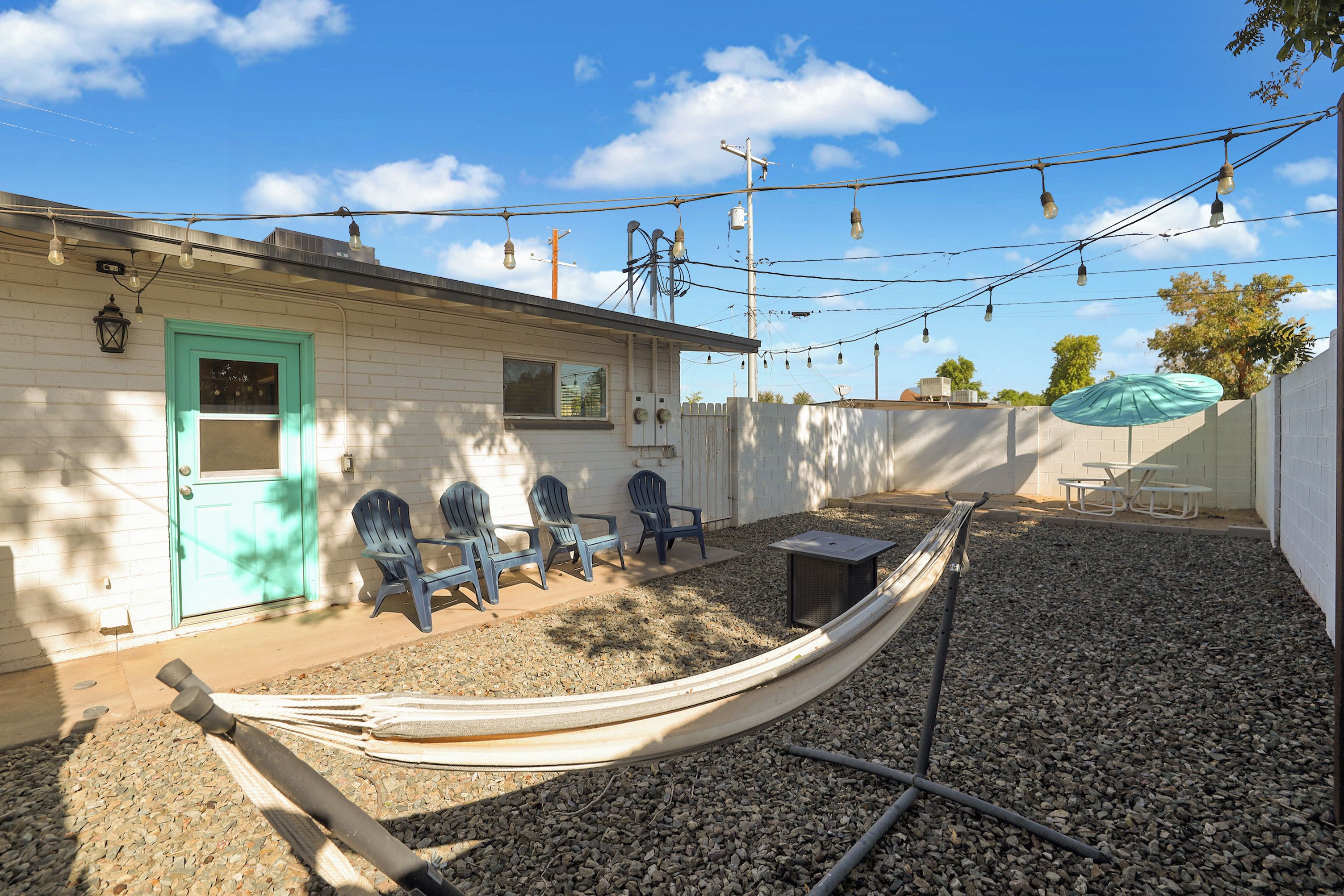 A house with a green door, outdoor seating, and a hammock.