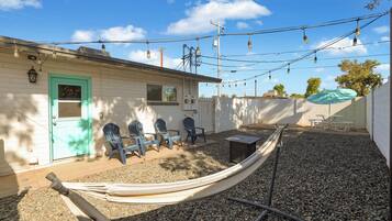 A house with a green door, outdoor seating, and a hammock.