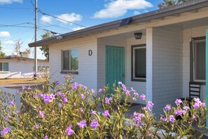 A single-story building with a white exterior, a green door, and a window marked with the letter 'D'.