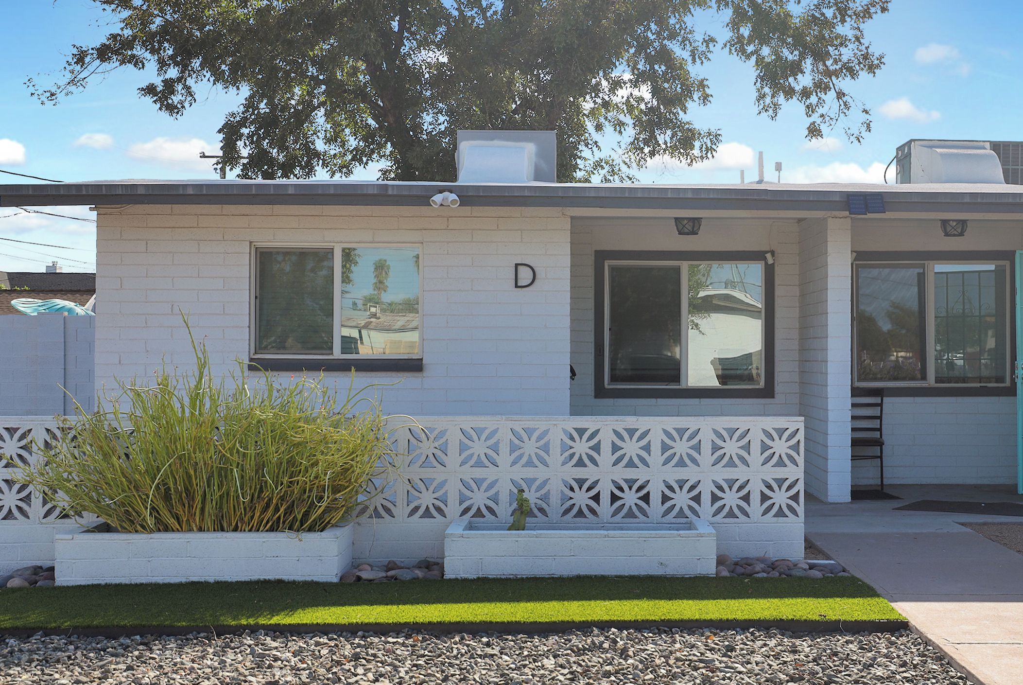 A modern building with a white facade, two windows, and a small garden area with plants.