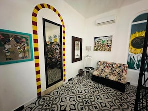 Un pasillo con suelo estampado, un espejo, un sofá y obras de arte en las paredes.