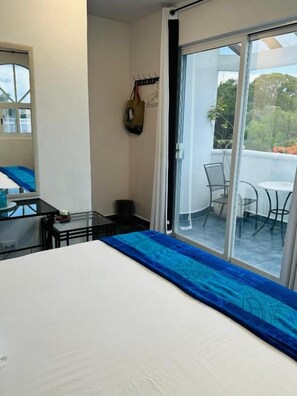 A hotel room with a bed, a small table, a chair, and a balcony with a view. - The Quetzal Cancun (Cancún)