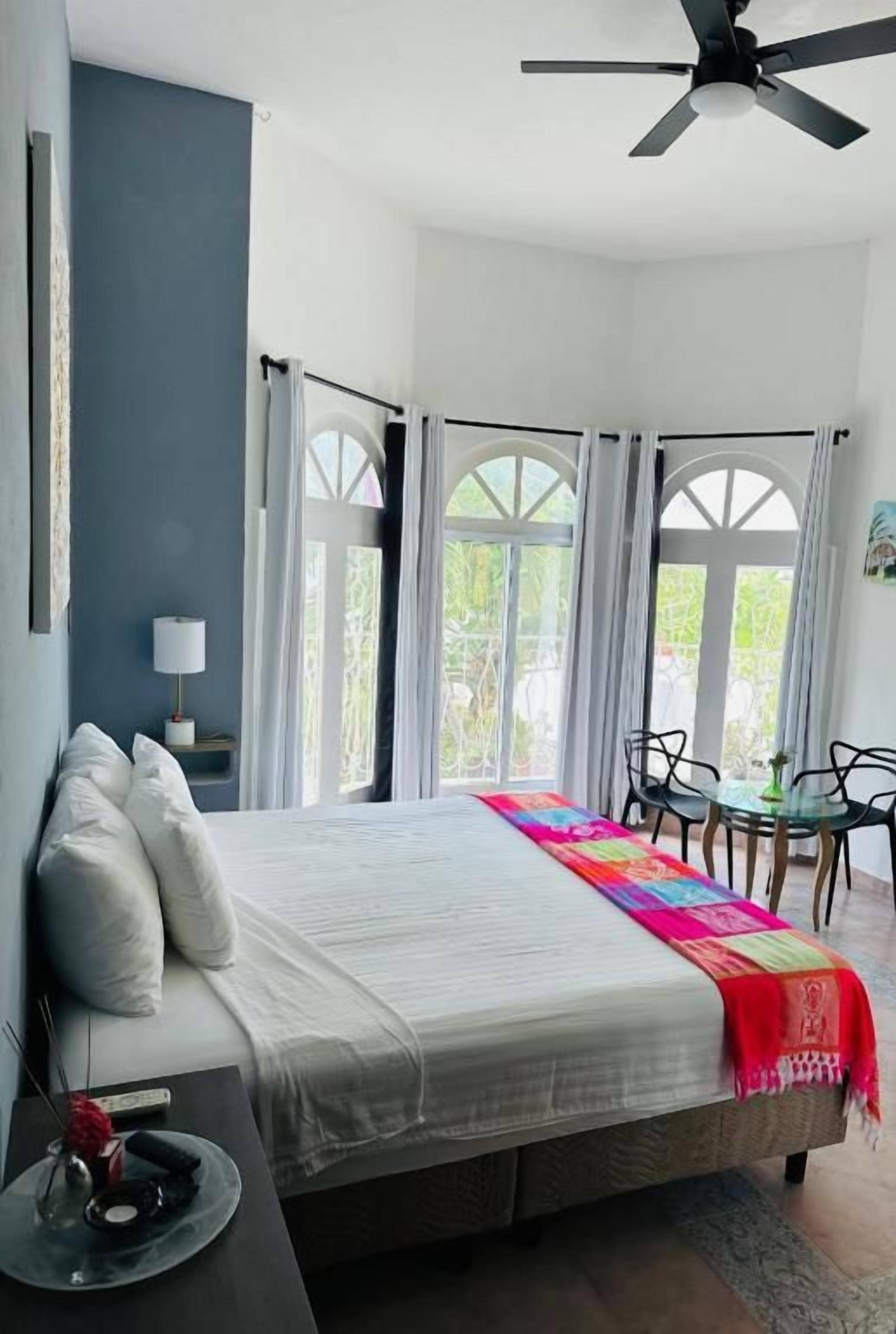 A bedroom with a bed, a bedside table, a chair, and a window with curtains.
