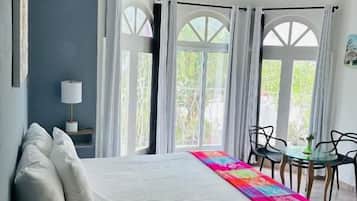 A bedroom with a bed, a bedside table, a chair, and a window with curtains.