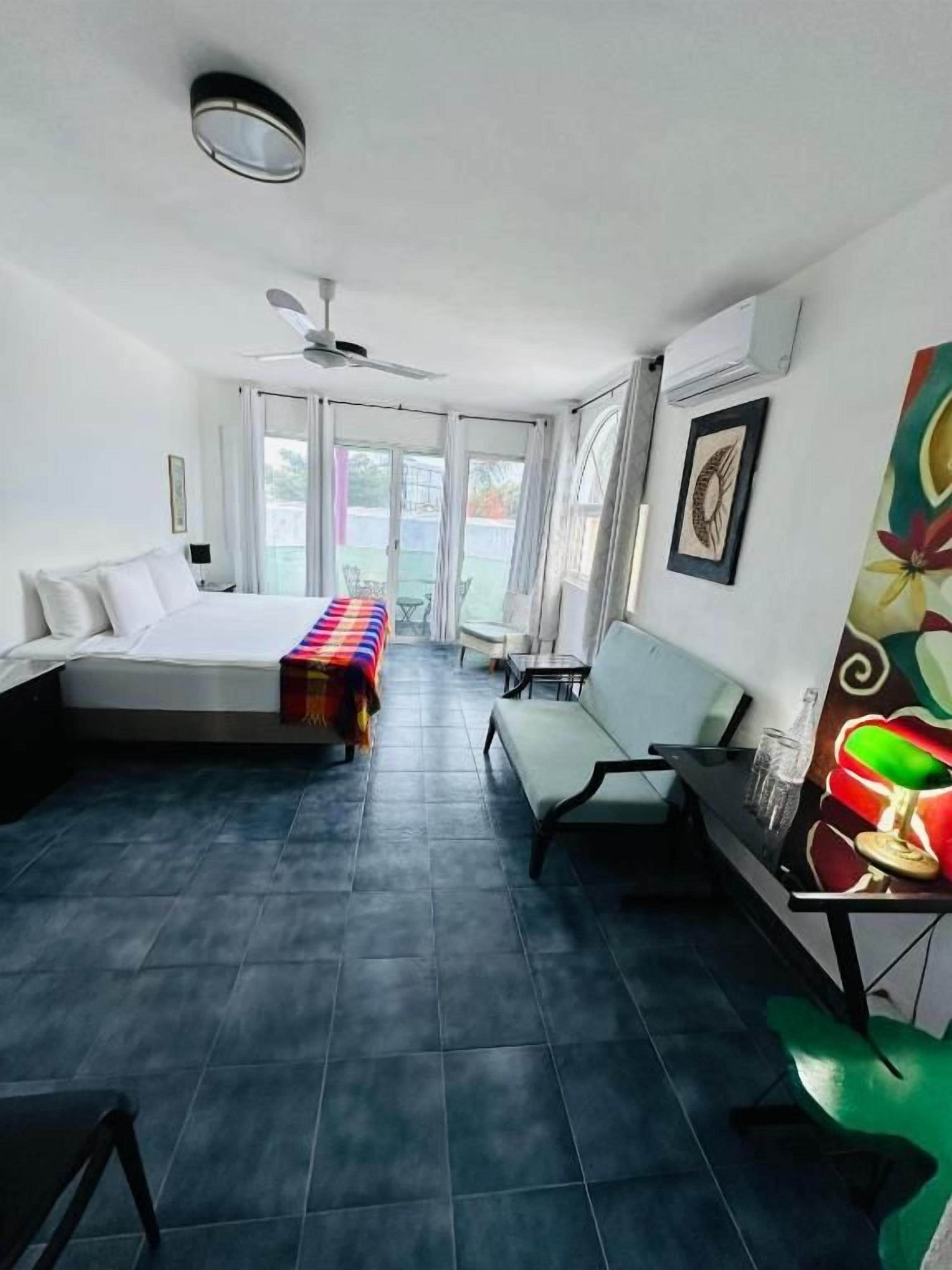 Een kamer met een bed, een bankje, een tafel met een glas en een raam.