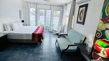 Een kamer met een bed, een bankje, een tafel met een glas en een raam.