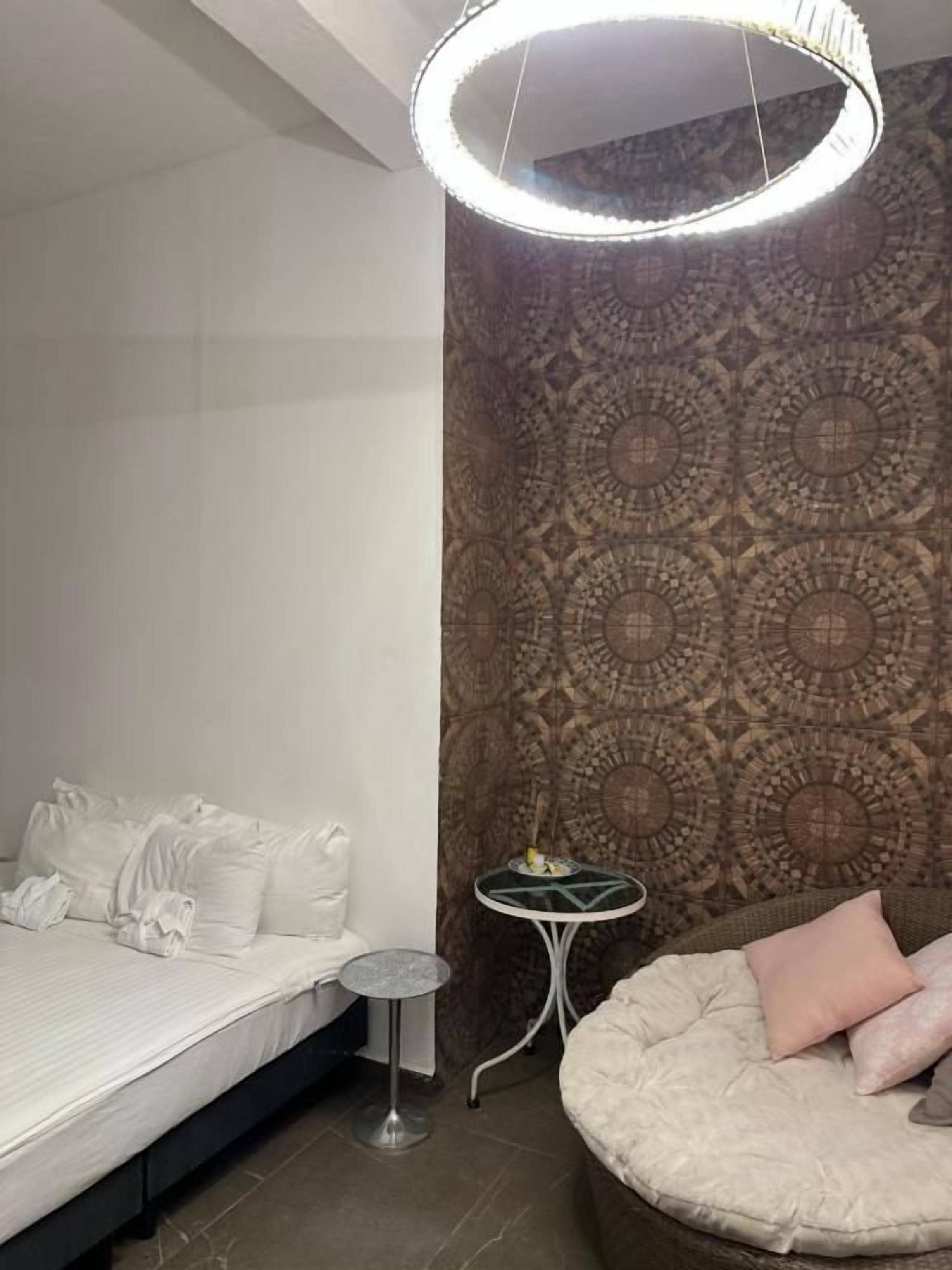 A bedroom with a bed, bedside table, and a circular light fixture.