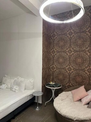 Un dormitorio con cama, mesita de noche y lámpara circular.
