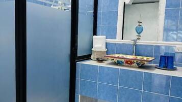 A bathroom with a glass partition, a sink with a mirror, and a towel rack.