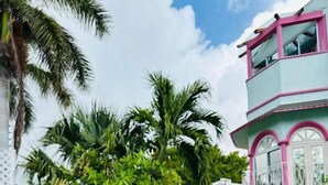 A swimming pool with a white deck, surrounded by tropical plants and a multi-story building with pink accents. - The Quetzal Cancun (Cancún)