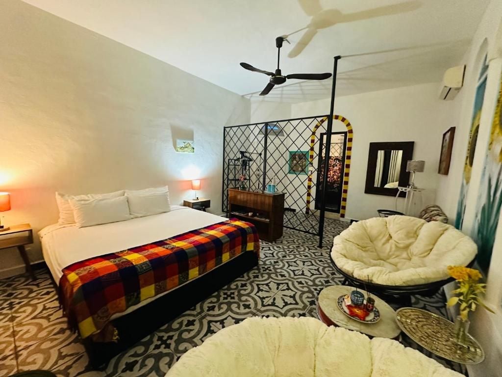 A bedroom with a bed, a chair, a desk, a ceiling fan, and a patterned floor.