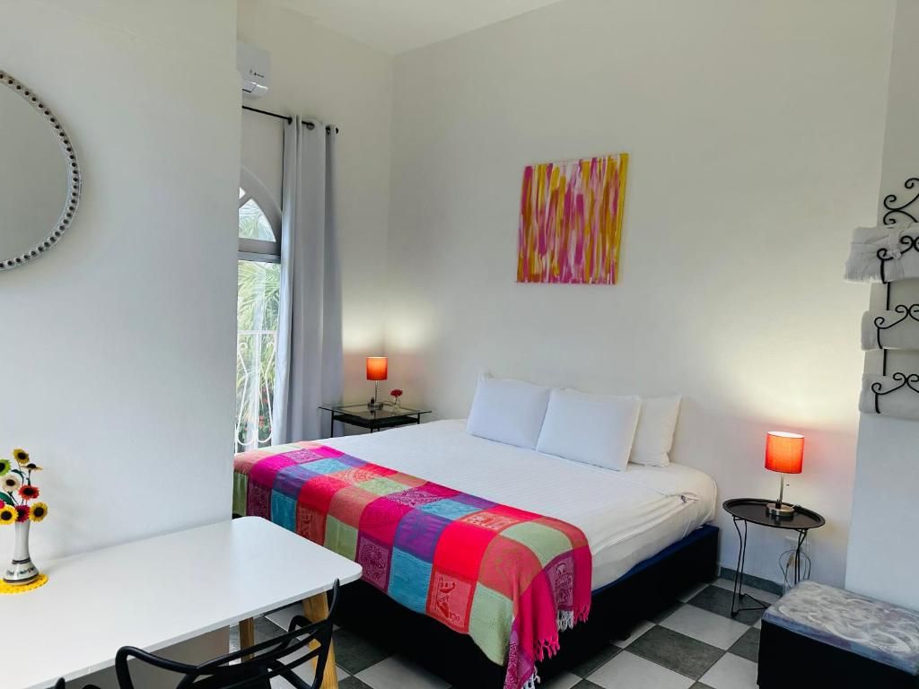 A hotel room with a bed, bedside tables, a desk, and a chair.