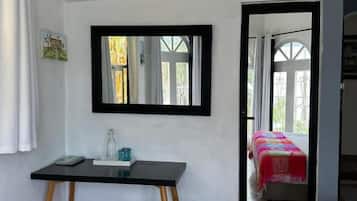Ein Zimmer mit einem Bett, einem Schreibtisch mit Spiegel und einem Fenster.