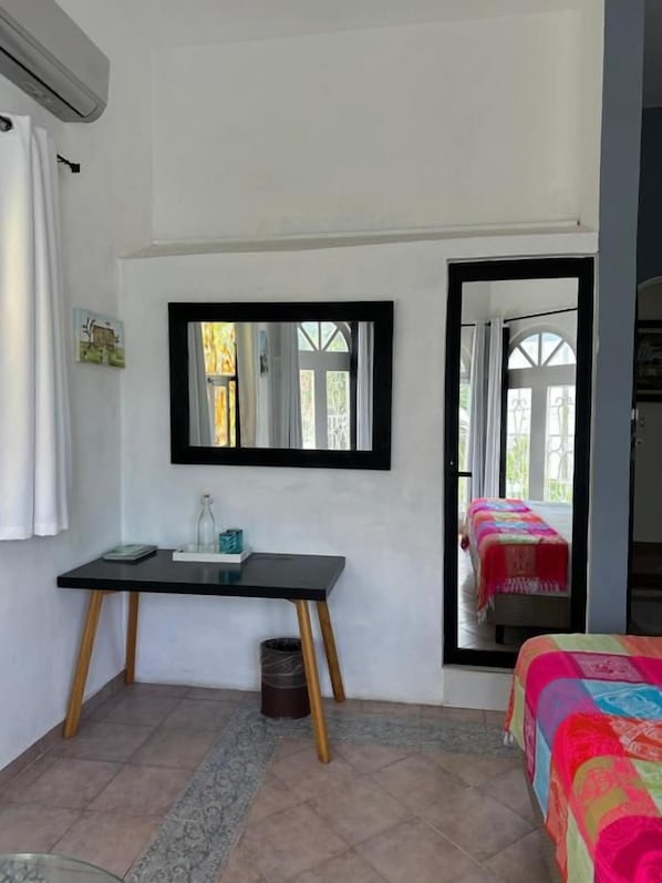 Una habitación con una cama, un escritorio con espejo y una ventana.