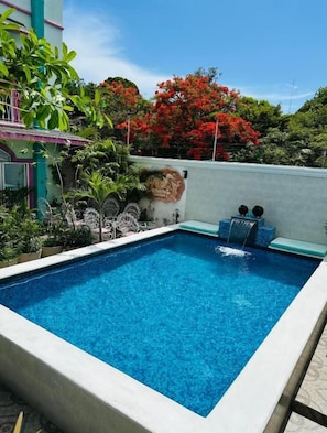 Una piscina rectangular con agua azul cristalina, rodeada por un solárium blanco.