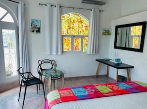 A room with a bed, a desk, a chair, a window with curtains, and a mirror on the wall.