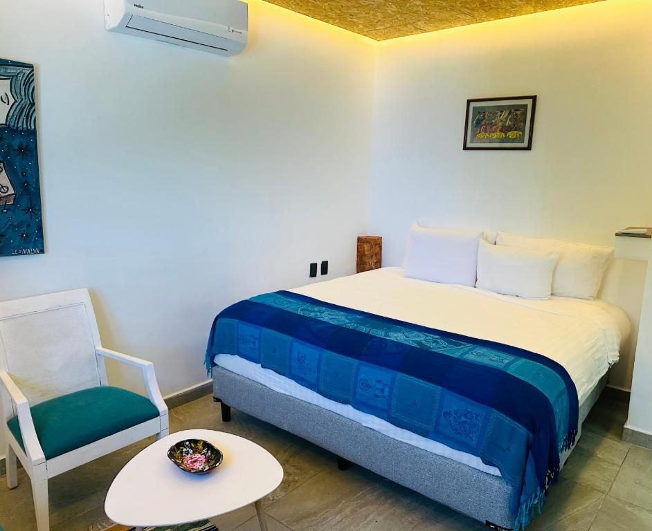 Habitación de hotel con cama, una silla, una mesita y aire acondicionado instalado en la pared.