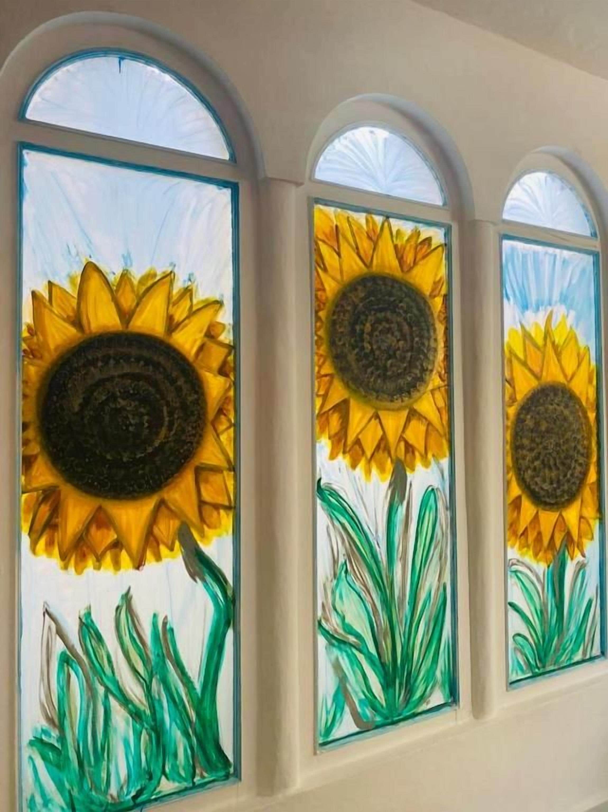 Tres girasoles pintados en los cristales de las ventanas.