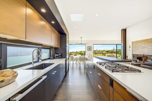 A modern kitchen with a view of a coastal landscape. - Soledad Sky House | Pool + Sweeping Ocean Views (San Diego)