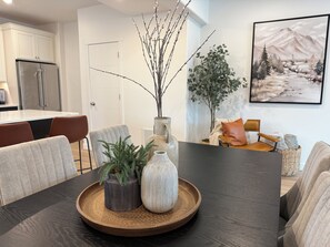A dining area with a dark wooden table, two potted plants, and a decorative vase. - 3-Bedroom Townhouse with Mountain and Lake Views. Sleep 9 (Heber City)