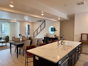 A modern kitchen with a large island, built-in appliances, and a dining area with chairs and a table. - 3-Bedroom Townhouse with Mountain and Lake Views. Sleep 9 (Heber City)