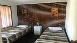 Ein Zimmer mit zwei Betten, einem weißen Schminktisch und einer Backsteinwand.